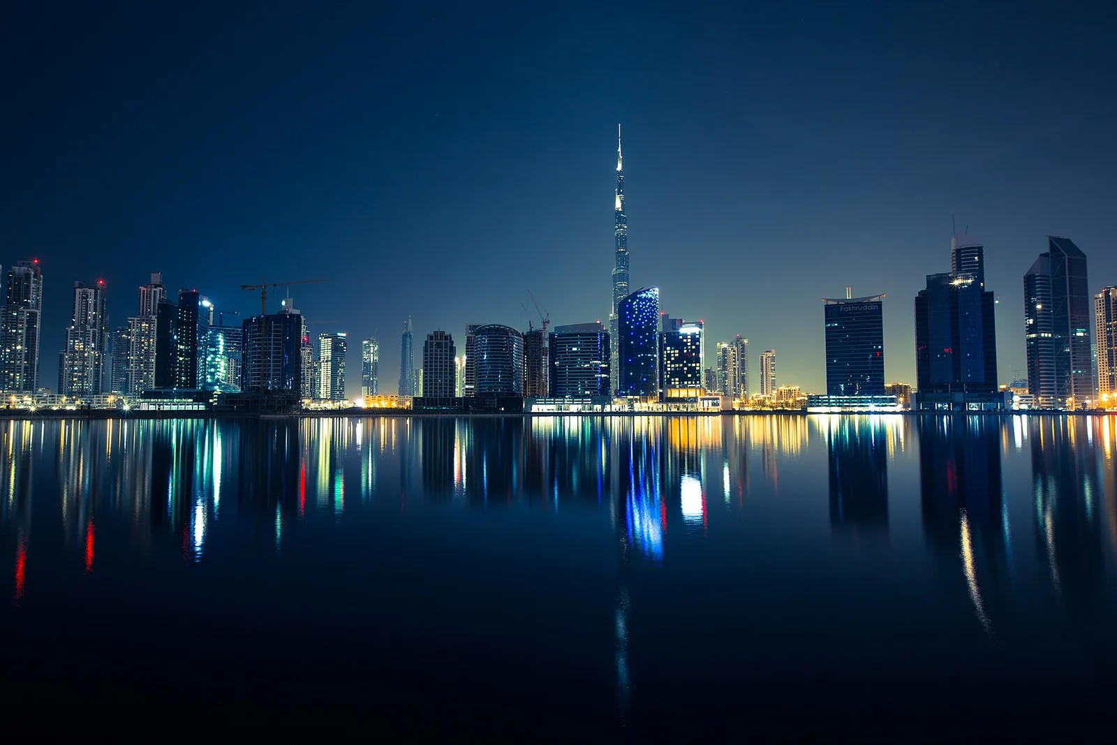 Dubais beleuchtete Skyline mit Spiegelungen im Wasser