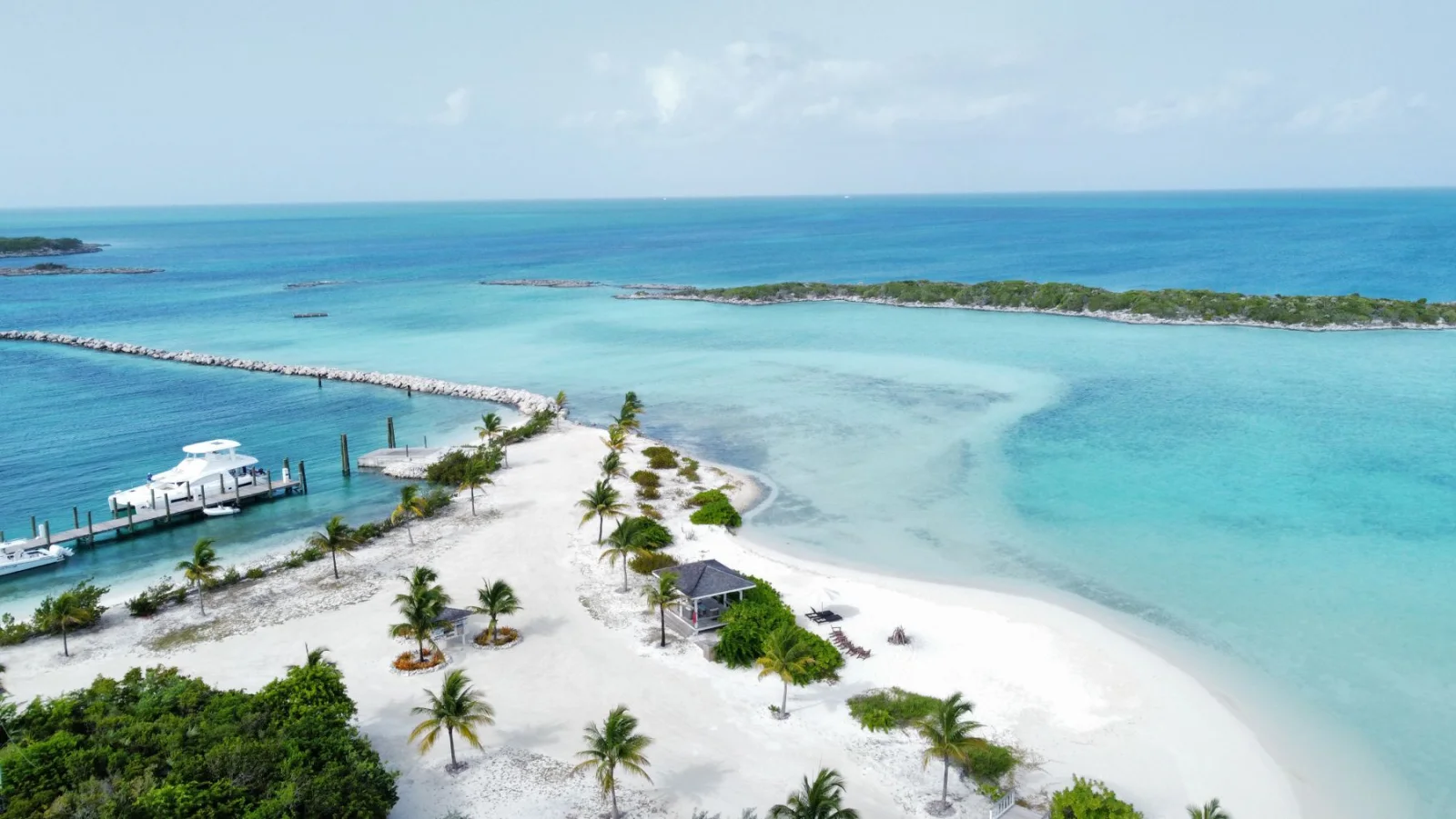Weißer Sandstrand mit Palmen und Yachten am türkisfarbenen Wasser auf den Bahamas