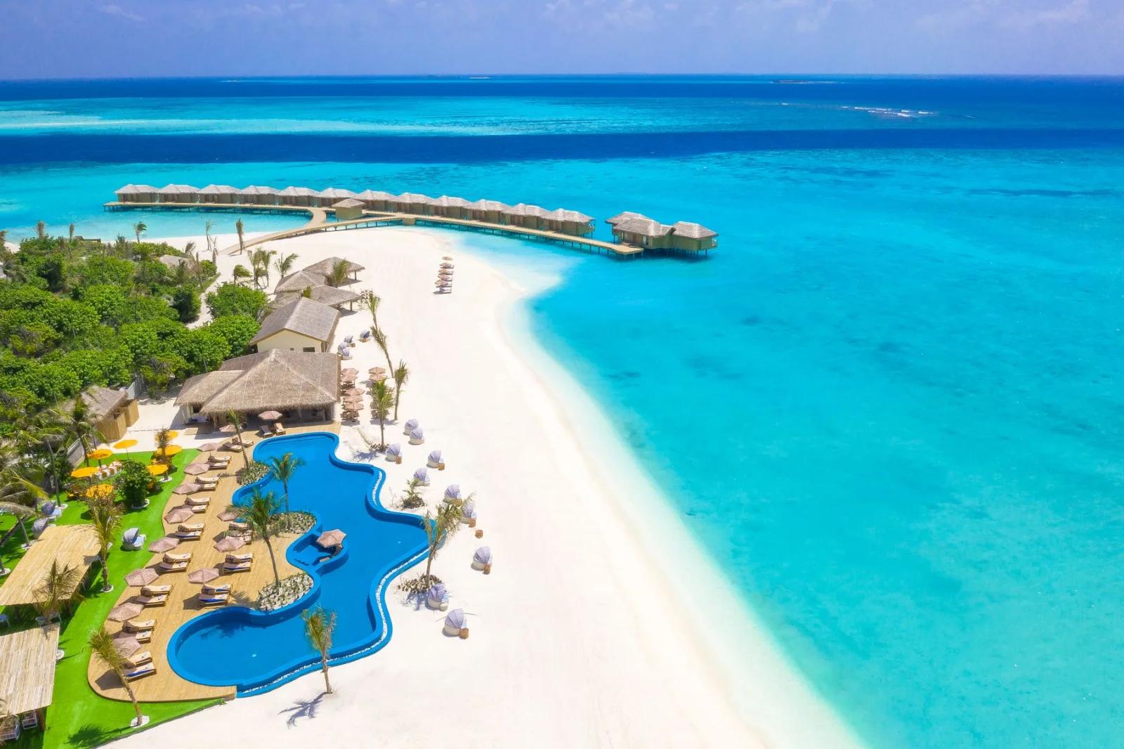 Weißer Sandstrand, türkisfarbene Lagune und Wasservillen eines Resorts auf den Malediven