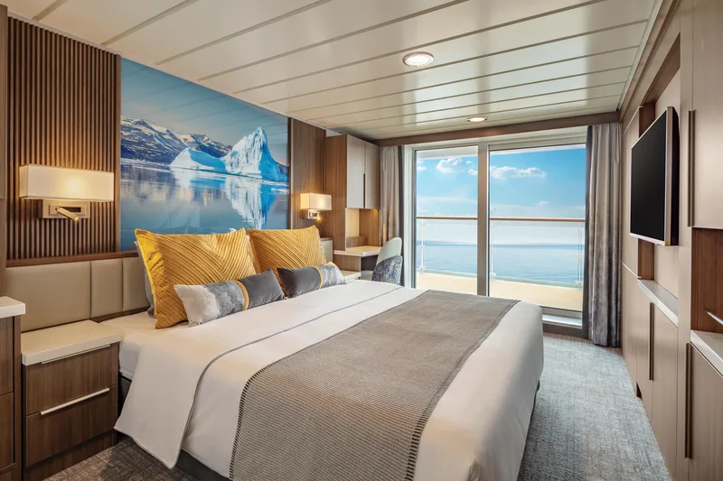 Junior Suite auf der Sylvia Earle mit Doppelbett und Blick durch die Balkontür aufs Meer