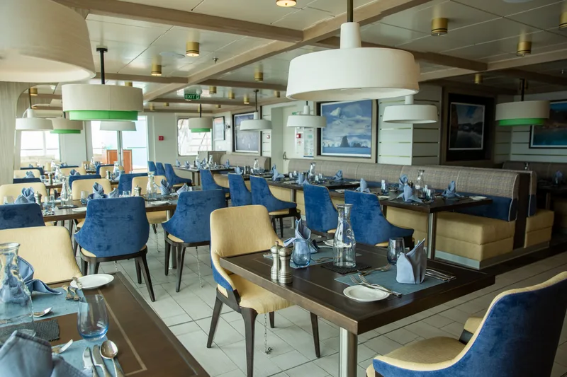 Gedeckte Tische und blaue Sessel im Rockhopper Restaurant auf der Sylvia Earle