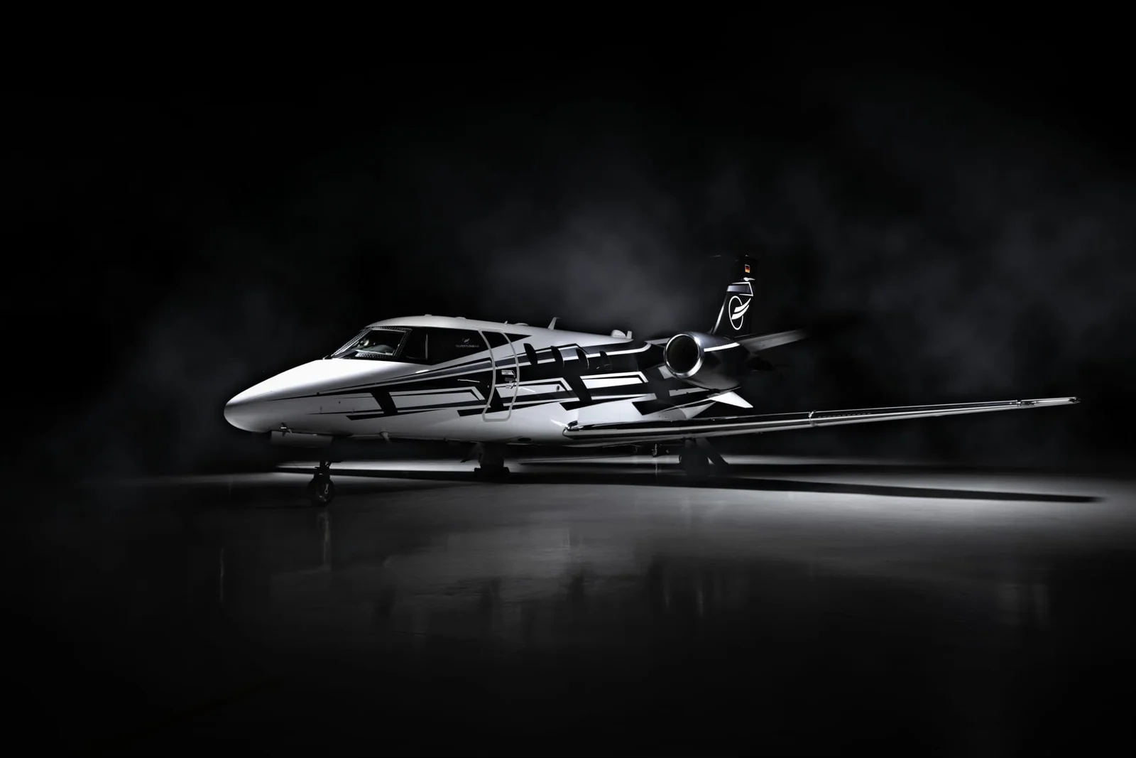 Cessna Citation XLS+ after refurbishment, with its personalised black-and-white paint scheme in a dark hangar.